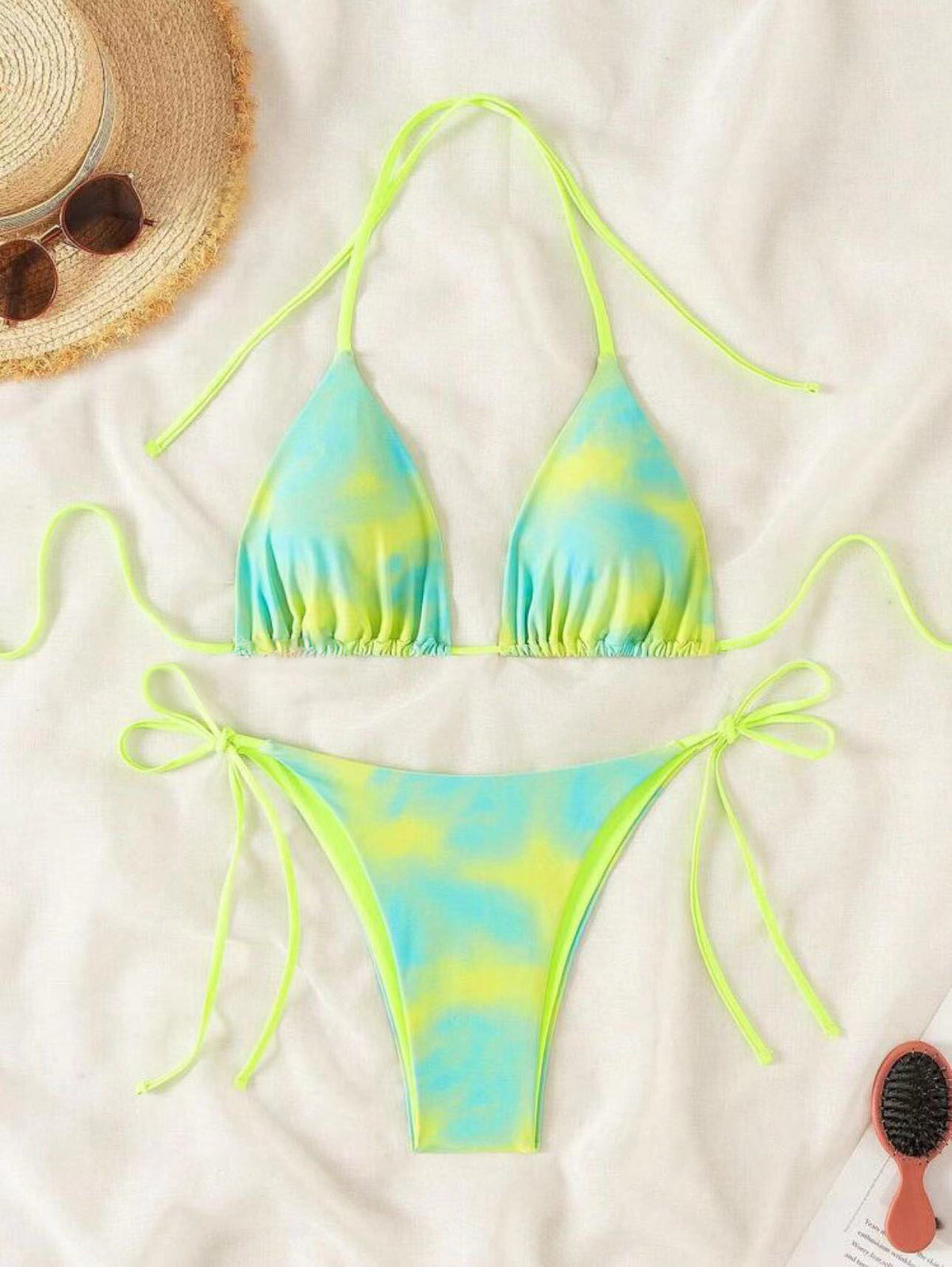 A two-piece swimsuit with blue tie-dye patterns and brown lacing details on a white background.