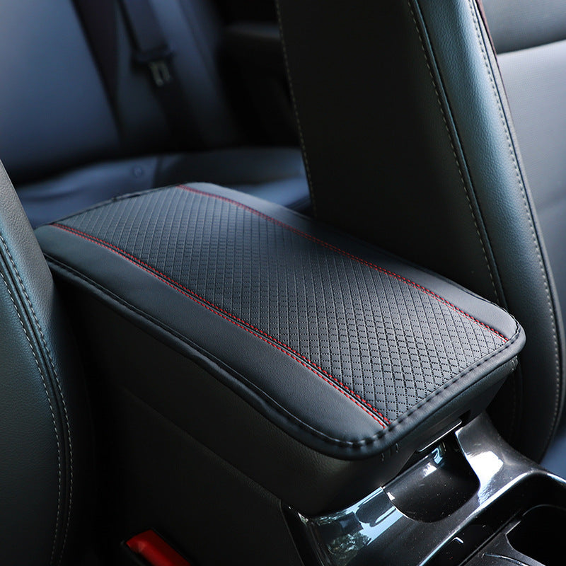 A black automotive fiber leather armrest box mat with red embossed pattern, installed on a car's center console.