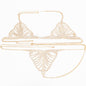 A woman wearing a gold-colored body chain that connects to a bra and panties, laid out on a bed.