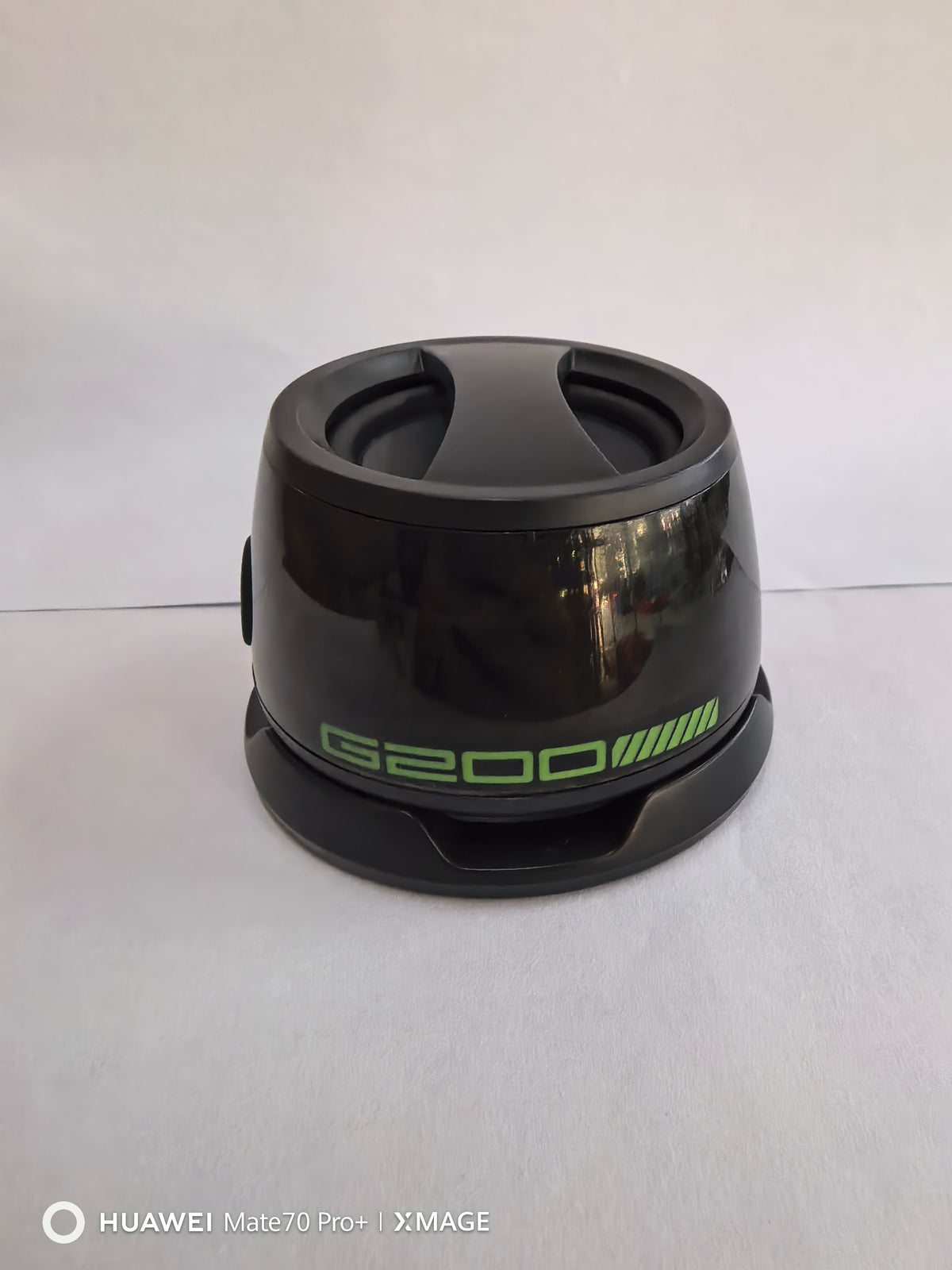 A portable Bluetooth speaker with RGB lighting, displayed in a transparent case, showing internal components and a magnetic phone holder.