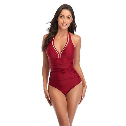 A woman wearing a red halterneck one-piece swimsuit with lace-up details at the front.