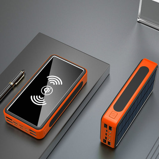A solar power bank with an orange and black color scheme, showing the solar panels on the top and the brand logo on the front. A smartphone is being charged on it.