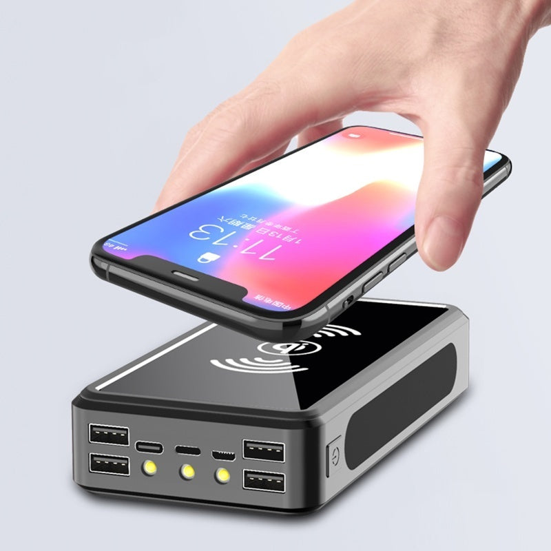 Hand holding a smartphone above a wireless charging station.