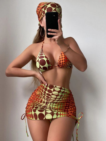 Person wearing a colorful patterned bikini and headscarf taking a mirror selfie.