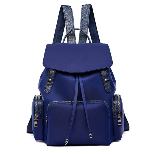 A blue Oxford cloth backpack with a vertical square shape, featuring a cover opening with tape drawing, multiple shoulder straps, and a telescopic handle.