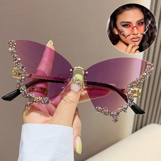 A pair of luxury diamond butterfly sunglasses with a rimless, oversized design. The sunglasses have a gradient color and are adorned with diamonds along the frame.