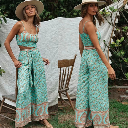 A model wearing a vintage boho print outfit which includes a sleeveless top and wide leg pants. The outfit is predominantly in shades of green with a floral and geometric pattern.