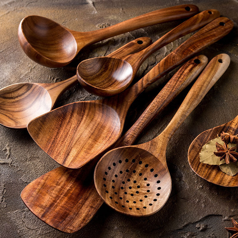 Wooden cooking utensils on a stone surface.