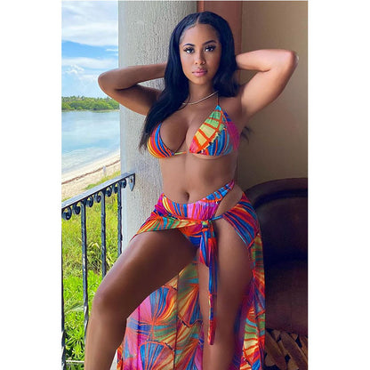 A woman wearing a multicolored geometric patterned three-piece bikini swimwear with a matching cover-up skirt.