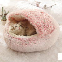 A pet (cat) resting inside a round plush pink bed with a drawstring closure.
