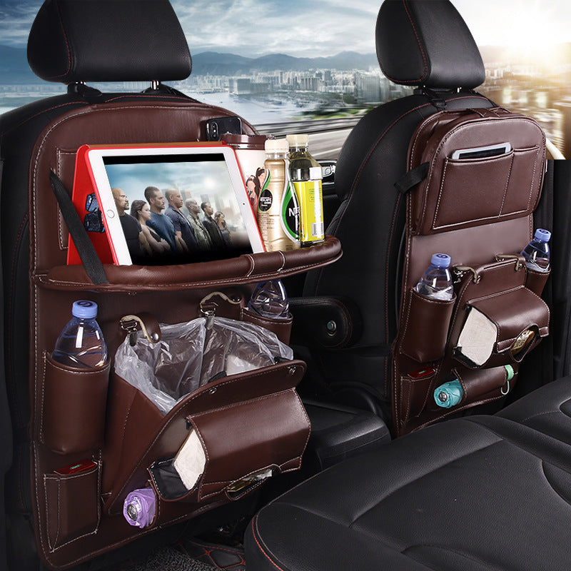 A multifunctional car storage hanging bag attached to the back of a car seat, featuring pockets with various items such as bottles and a tablet, and a built-in trash can.
