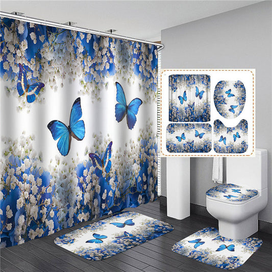 A set of bathroom accessories featuring a shower curtain with blue floral and butterfly patterns, including a bath mat, toilet cover, and possibly a seat cover.