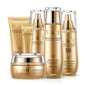 A set of six skincare products in golden and white packaging, labeled for different skin care purposes such as cleanser, cream, toner, lotion, eye cream, and BB cream.