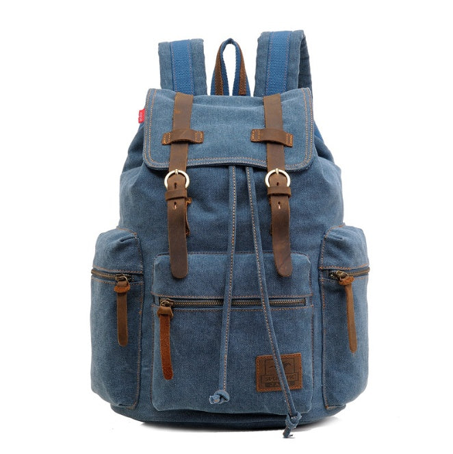 Blue denim backpack with brown leather straps on a white background