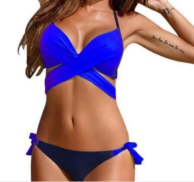 A woman wearing a pink and dark blue two-piece swimsuit with cross straps and a solid pattern.