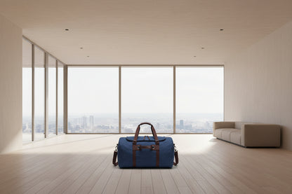 Blue suitcase with brown handle on a wooden floor in a modern room with large windows.