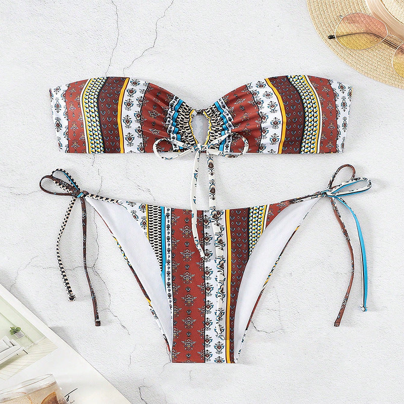 A woman wearing a multicolored printed lace-up split swimsuit bikini sitting on a wicker chair.