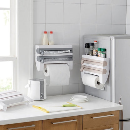 A white 4-in-1 kitchen roll holder dispenser mounted on a wall, holding a paper towel roll, a foil roll, and a plastic wrap roll.