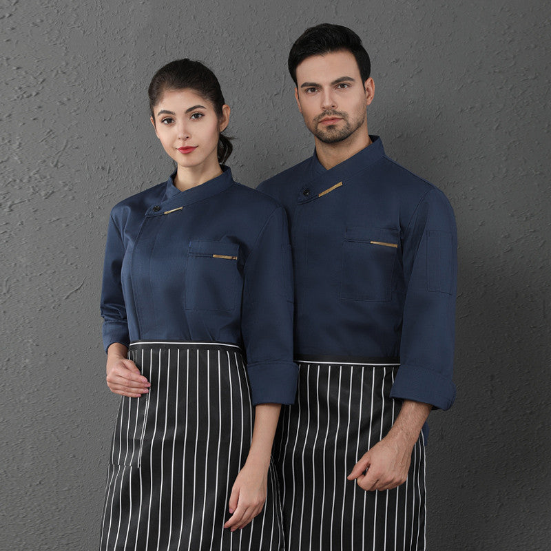 A male and a female chef wearing long sleeved chef coveralls in blue with white aprons.