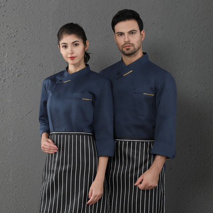 A male and a female chef wearing long sleeved chef coveralls in blue with white aprons.