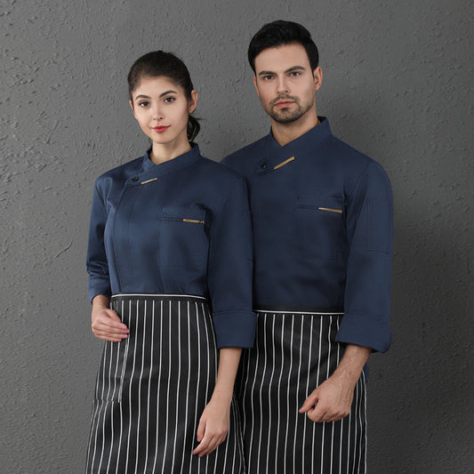 A male and a female chef wearing long sleeved chef coveralls in blue with white aprons.
