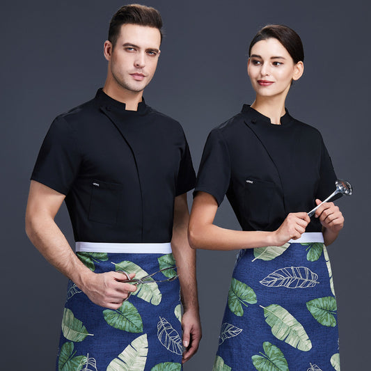 A male and a female chef wearing black short-sleeve chef shirts with a floral pattern on the apron.