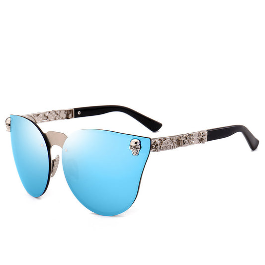 A pair of sunglasses with blue lenses and a patterned metal frame, including a small skull design on one side.