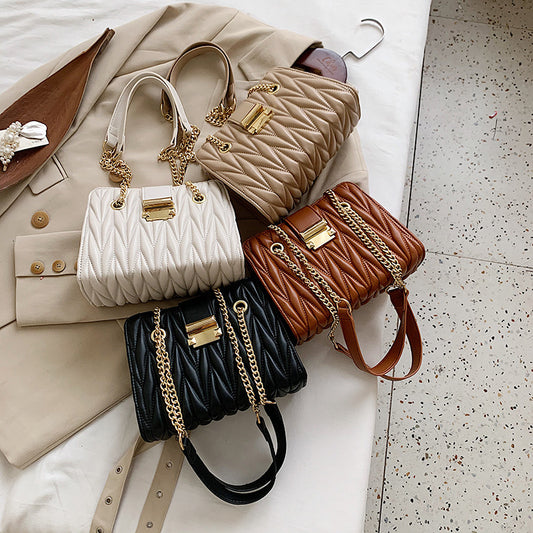 A collection of pleated chain handbags in beige, brown, and black colors displayed on a flat surface.