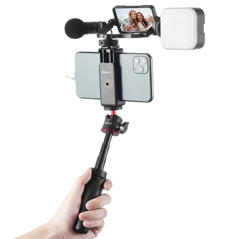 Handheld video recording setup with microphone and lighting on a white background