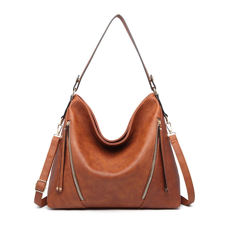 A brown, faux leather handbag with a shoulder strap, external pocket zippers, and a bucket shape design.