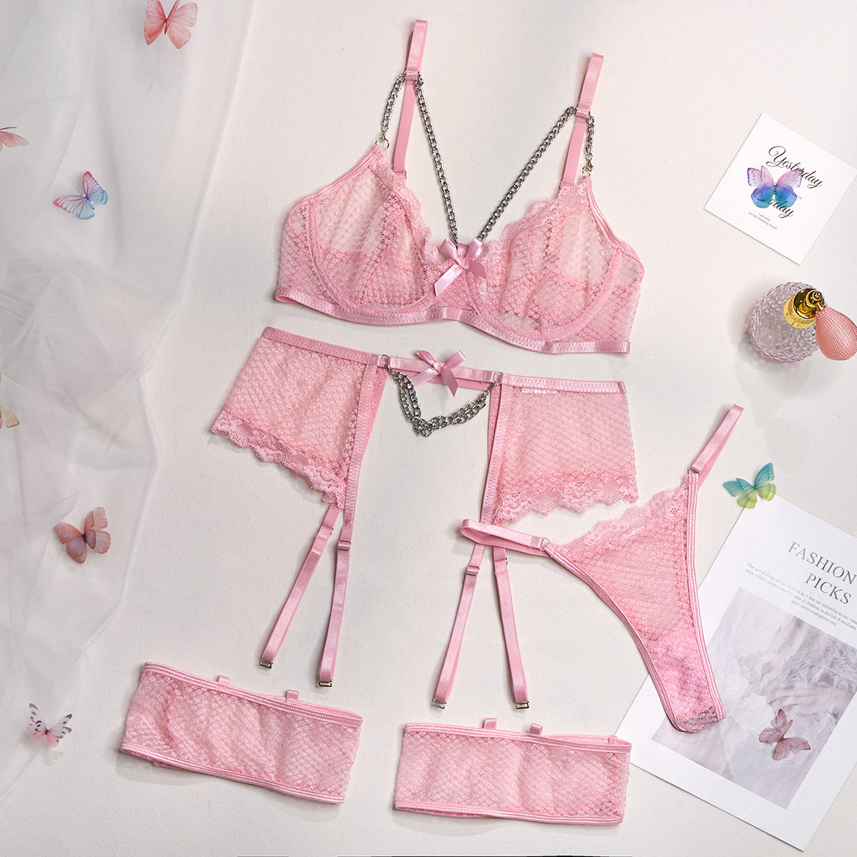 A woman modeling a pink lingerie set which includes a bra, panties, and garter straps.