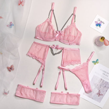 A woman modeling a pink lingerie set which includes a bra, panties, and garter straps.