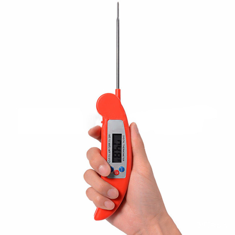 A hand holding a red folding food thermometer with a digital display.