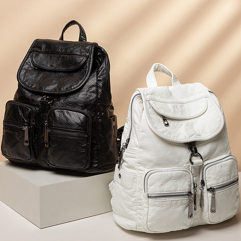 Two large-capacity backpacks, one black and one white, with multiple pockets and locks, displayed on a white pedestal.