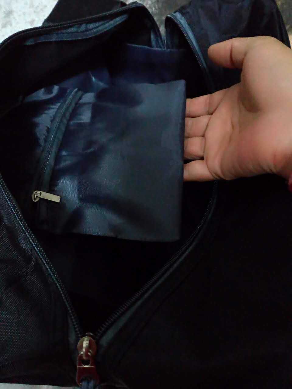 Person opening a dark blue jacket zipper.