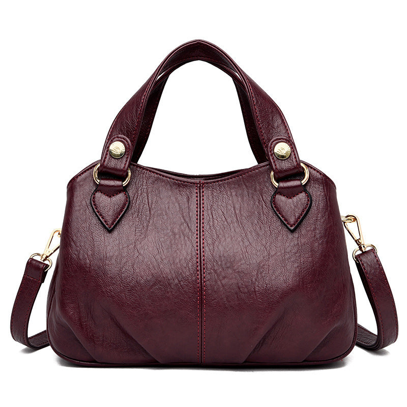A wine red multifunctional handbag with sheepskin stitching, featuring a soft leather exterior and a shoulder strap.