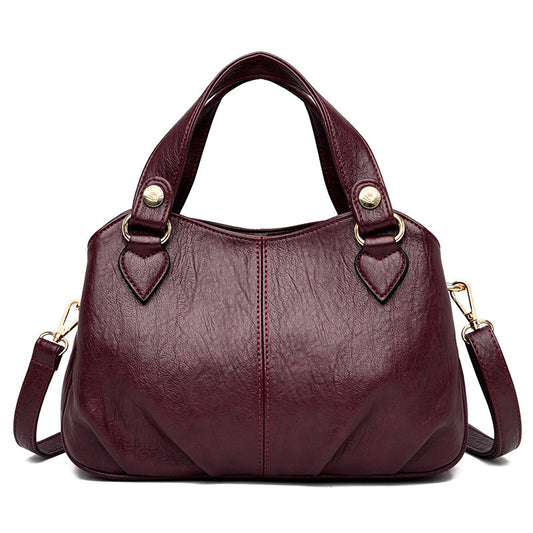 A wine red multifunctional handbag with sheepskin stitching, featuring a soft leather exterior and a shoulder strap.