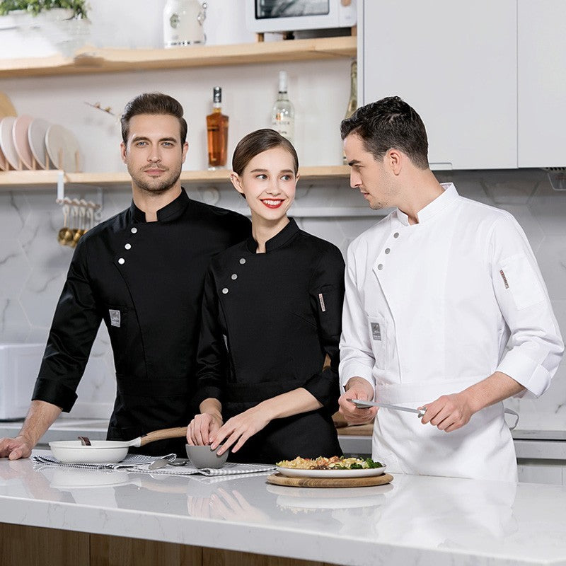 Two adults, one male and one female, wearing long sleeve chef uniforms in a kitchen setting. The male chef is in a white uniform, and the female chef is in a black uniform.