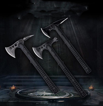 Two black multi-functional camping axes with different designs, one with a pointed tail and the other with a hammer head, displayed against a dark, moody background with a reflective surface.