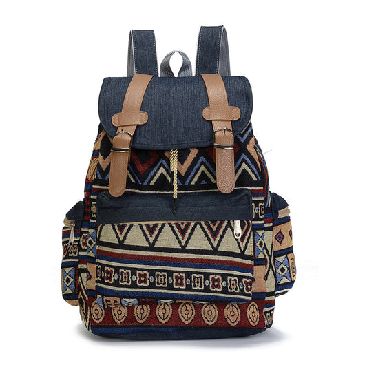 A multicolored ethnic style women's backpack with geometric patterns, featuring a denim material, leather straps, and a soft handle.