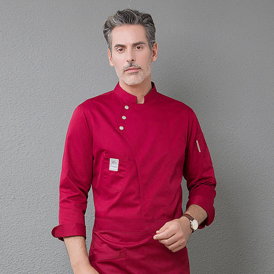 A male model wearing a red chef uniform with a name tag, standing against a grey background.