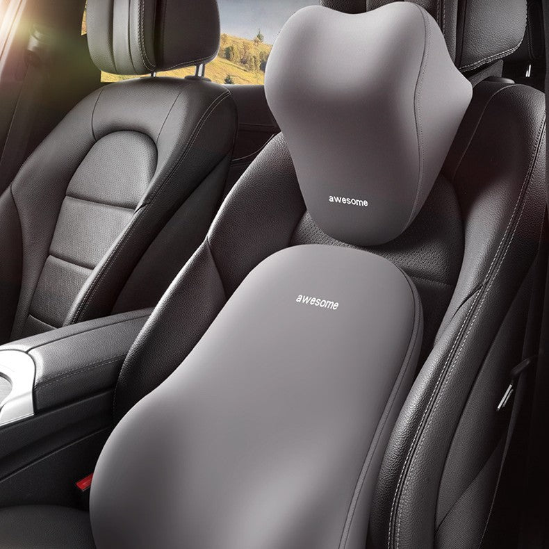 A gray automotive headrest lumbar support pillow installed on a car seat, with a blurred background.