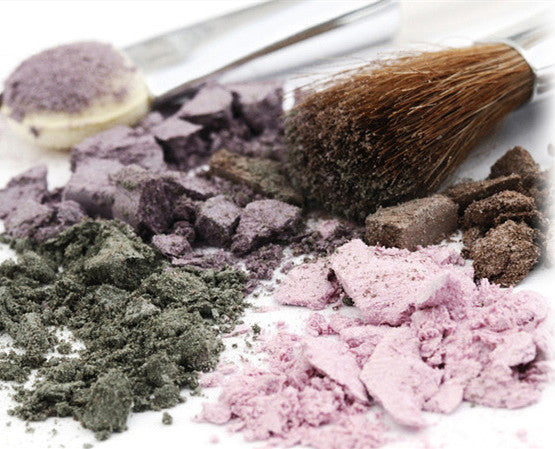Colorful makeup powder with a brush and spoon on a white background
