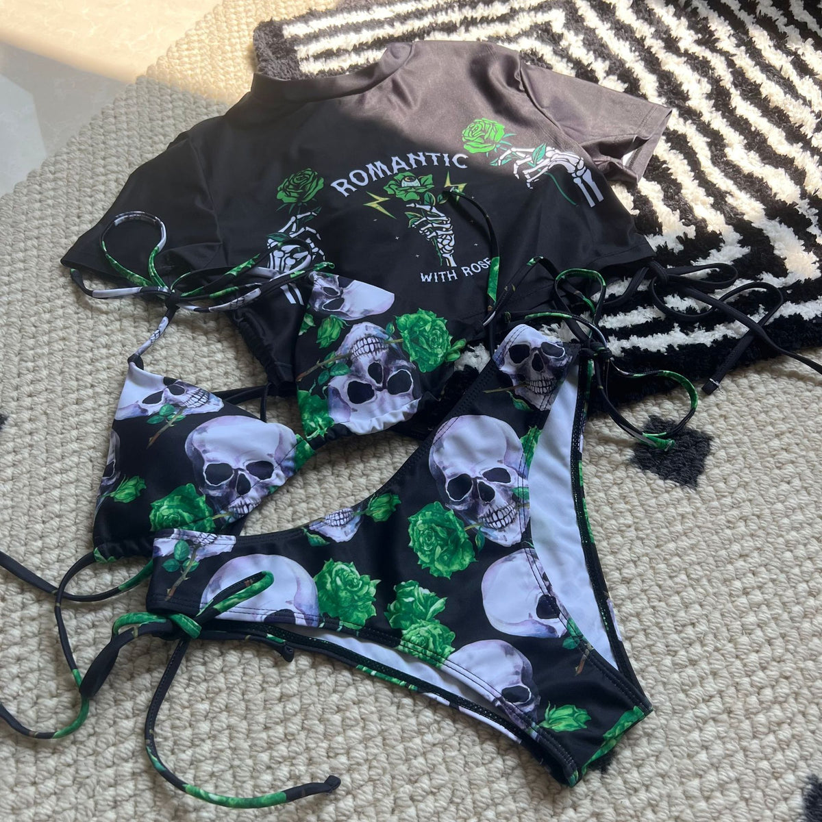 Two swimsuits with skull and floral pattern on a textured surface.