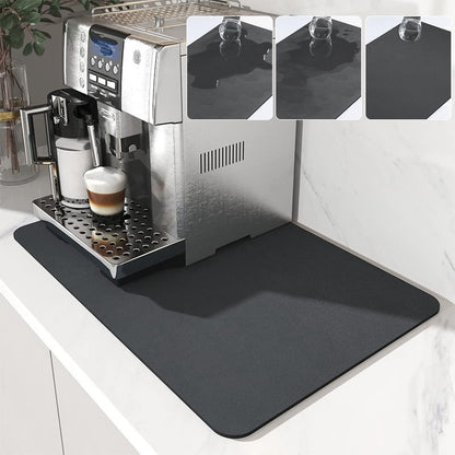 A black super absorbent drainer mat placed under a coffee machine on a kitchen countertop, with insets showing the mat's texture and foldability.