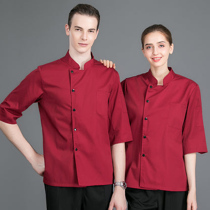 Two individuals wearing red chef suits with short sleeves, button-up front, and a chest pocket. One person has their hand on the other's shoulder.