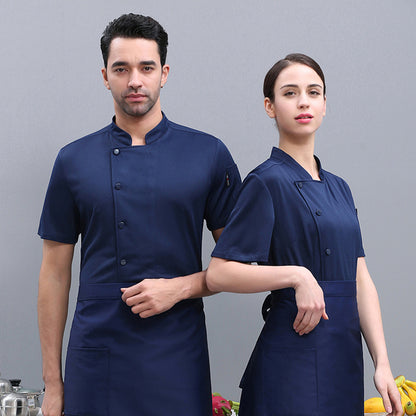 A male and a female model wearing navy blue short sleeve chef overalls, with the male model in front showing a three-quarter turn and the female model behind him showing a full face profile.