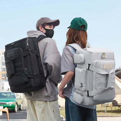 A man and a woman seen from behind, each carrying a large backpack. The man's backpack is black, and the woman's backpack is gray.