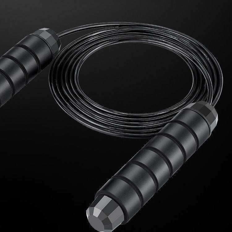 A black jump rope with foam handles and a steel wire rope.