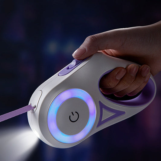 A retractable dog leash with a built-in spotlight, held in a person's hand. The leash is purple, and the handle features a button and LED light.